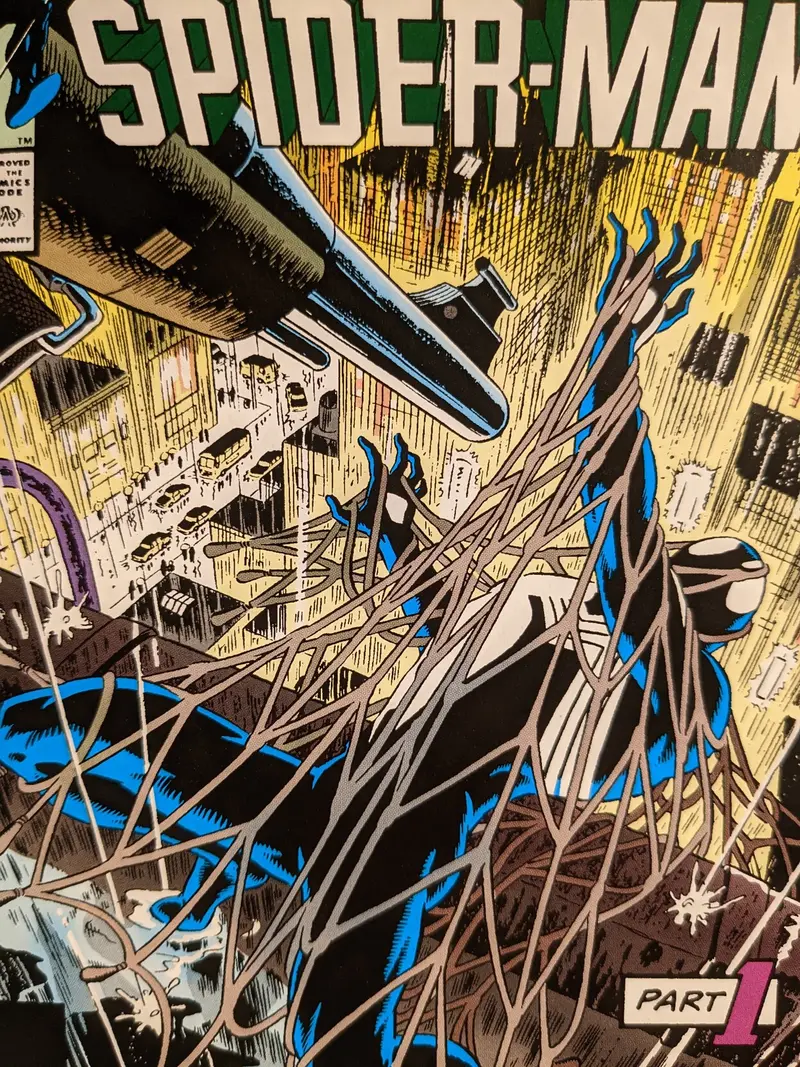 Portada del primer número Spiderman con el traje negro envuelto en una red y apuntado por una pistola.